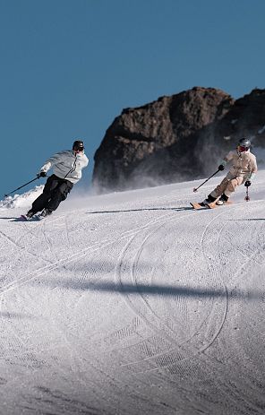 zwei Skifahrer auf der Piste in der Kurve in den Tiroler Bergen während Skiurlaub